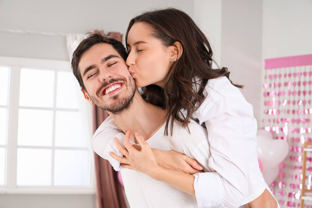 Joyeux jeune couple embrassant dans la chambre à coucher le jour de la Saint-Valentin, gros plan - Photo, image