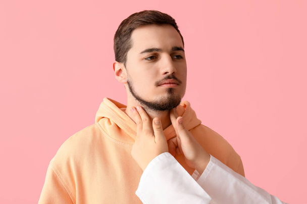 Endokrinologi tutkii nuoren miehen kilpirauhasen vaaleanpunaisella taustalla - Valokuva, kuva