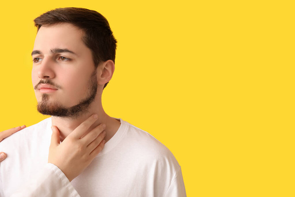 Endocrinólogo examinando la glándula tiroides del hombre joven sobre fondo amarillo - Foto, imagen
