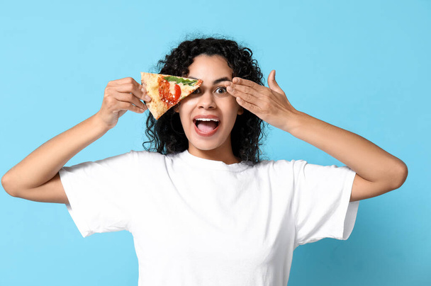 青い背景においしいピザのスライスと美しい若い幸せなアフリカ系アメリカ人女性 - 写真・画像