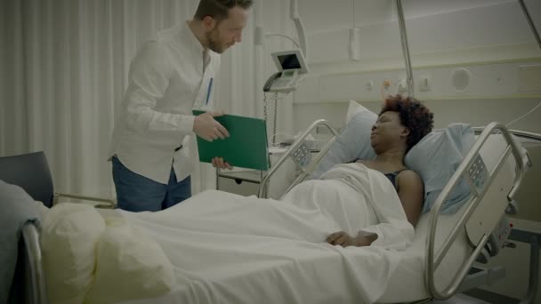 Medico visita paziente in camera d'ospedale spiegando il trattamento medico di cura della salute - Filmati, video