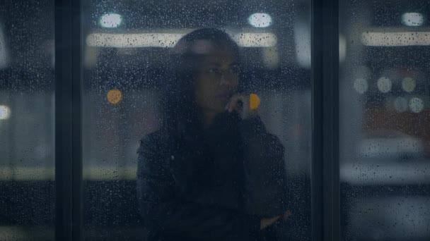 Przemyślana młoda kobieta myśląca o życiu poza deszczem w nocy - Materiał filmowy, wideo
