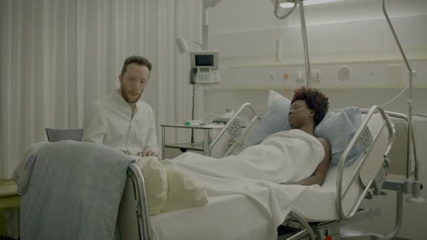 Lékař navštíví pacienta v nemocničním pokoji vysvětlující lékařské ošetření - Záběry, video