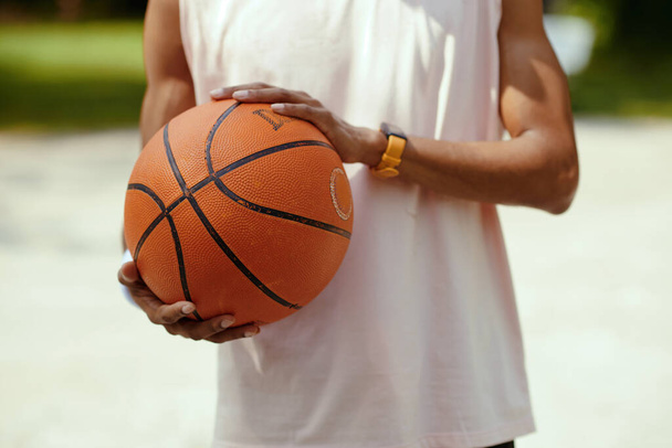 Καλλιεργημένη εικόνα του παίκτη streetball κρατώντας μπάλα του μπάσκετ - Φωτογραφία, εικόνα