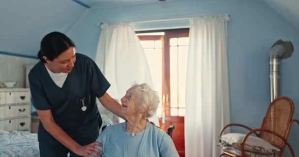 Cuidador hablando con una mujer mayor en silla de ruedas para obtener apoyo médico, rehabilitación y confianza en el hogar de ancianos. Enfermera hablando con paciente anciano con discapacidad, artritis y sanación en el dormitorio. - Imágenes, Vídeo