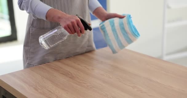 Καθαρίστρια με ποδιά ψεκάζοντας αντισηπτικό σε βρώμικο τραπέζι και σκουπίζοντάς το με κουρέλι closeup 4k ταινία αργή κίνηση. Υπηρεσίες καθαρισμού γραφείων και διαμερισμάτων - Πλάνα, βίντεο