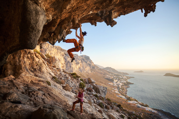 Jonge vrouw lood klimmen in grot - Foto, afbeelding