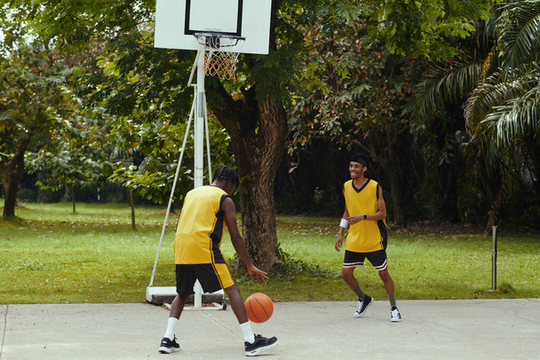 Veselý černošky mladí muži v uniformě hrát basketbal venku - Fotografie, Obrázek
