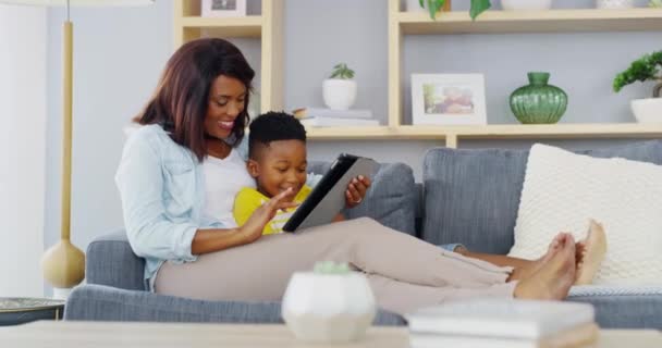 Child, mom and smile with tablet on sofa to play video games, watch movies and elearning app for kids at home. Mother, boy kid and black family streaming cartoon, digital ebook story or social media. - Footage, Video