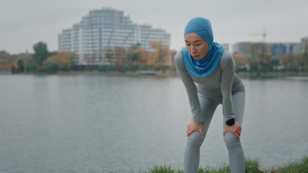 Vonzó muszlim nő futó pihenés kimerült után intenzív kardio edzés. Ázsiai hölgy atléta edzés közel a helyi tó. Fáradt lány edzés után kint. Kemény erőfeszítés Képzés Tartósság - Felvétel, videó