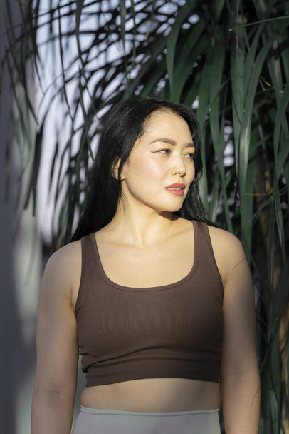 Egy fiatal ázsiai nő portréja zöld trópusi növények hátterével. Kiváló minőségű fénykép - Fotó, kép