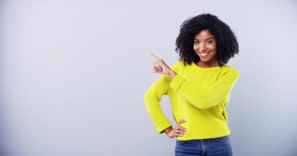 Smile, face and happy woman with hand pointing in studio for news, announcement or info on grey background. Space, portrait and female model show review, feedback or platform, opportunity or mockup. - Footage, Video