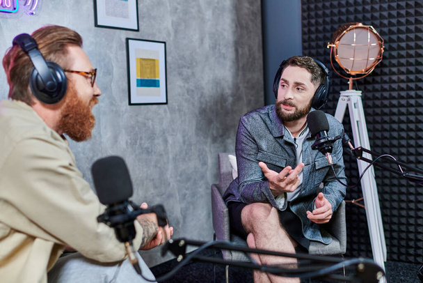 atraktivní reportér s rezavými vlasy a jeho host se sluchátky diskutovat otázky, podcast - Fotografie, Obrázek