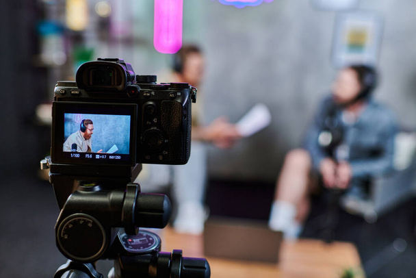 εστίαση στην κάμερα γυρίσματα όμορφος θολή άνδρες με γένια σε ακουστικά συζητώντας ερωτήσεις, πανό - Φωτογραφία, εικόνα
