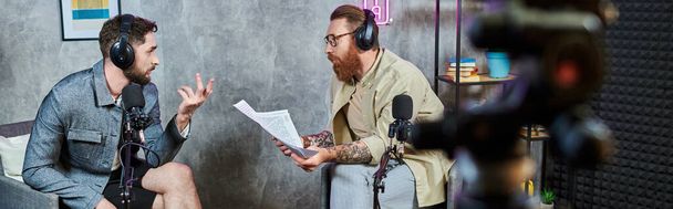 two handsome bearded men in casual attires with headphones talking actively during podcast, banner - Photo, Image
