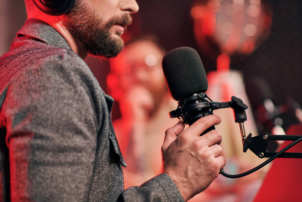 vágott fókuszált kilátás szakállas ember mikrofonnal az ő elmosódott interjúalany podcast - Fotó, kép
