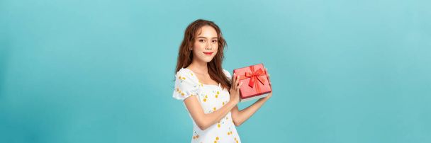 Portrait of happy charismatic girl shaking gift box wondering whats inside as celebrating birthday - Photo, Image