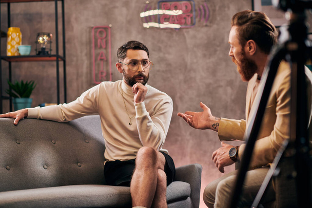 hombres barbudos de buen aspecto en elegantes trajes elegantes sentado y discutiendo preguntas de la entrevista - Foto, imagen