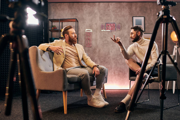 two elegant men with beards with dapper style sitting and discussing interview questions in studio - Photo, Image