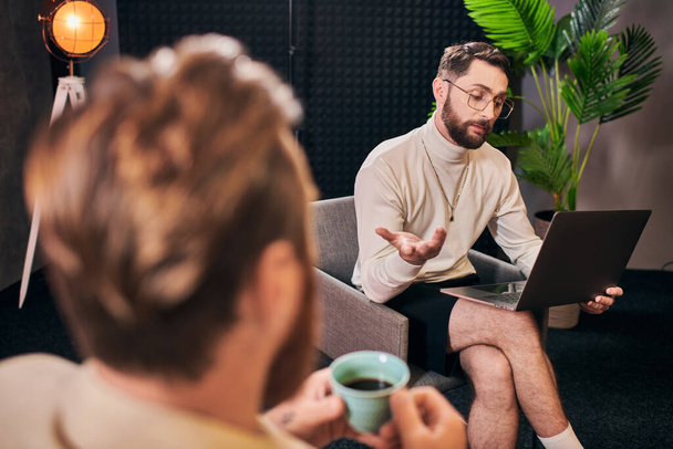 красиві шикарні чоловіки в елегантних сукнях з кавою і ноутбуком обговорюють питання інтерв'ю - Фото, зображення
