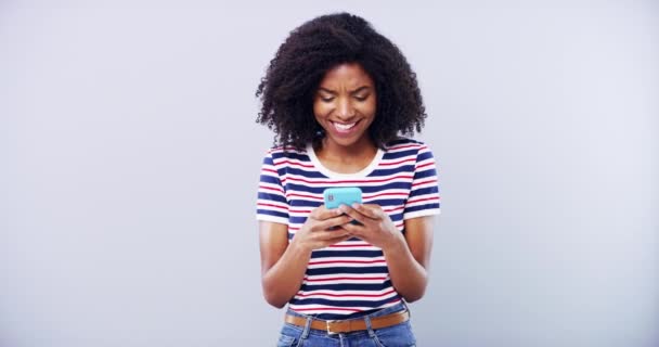 Schwarze Frau, die auf dem Smartphone tippt und im Studio lacht, isoliert auf einer Attrappe mit weißem Hintergrund. Porträt, Telefon und lustige Person scrollen auf mobiler App, Online-Meme oder Comedy-Witz in den sozialen Medien. - Filmmaterial, Video