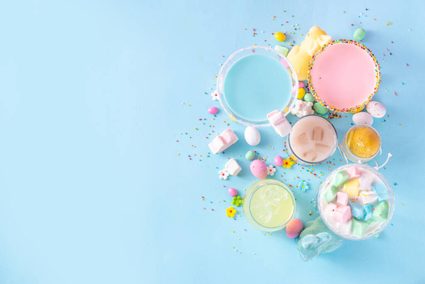 Πολύχρωμα παστέλ χρωματιστά παιδιά Πασχαλινά κοκτέιλ, Κρεμώδη και παγωμένα μη αλκοολούχα ποτά με μαλλί της γριάς, ζαχαρωτά και πασχαλινά αυγά, σε μπλε ροζ παστέλ φόντο αντίγραφο χώρου - Φωτογραφία, εικόνα
