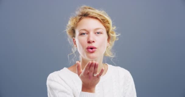 Woman, face and blowing kiss in studio for flirting, thank you or care gesture on gray background with mock up. Person, portrait and kissing emoji, expression or love for romance, gratitude and hands. - Footage, Video