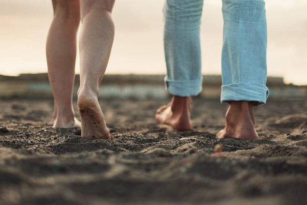 Close up and legs view for man and woman walking together on the ground in barefoot natural style. Concept of love and life together. Nudism. Couple of people walk. Sky in background. Travel. - Photo, image