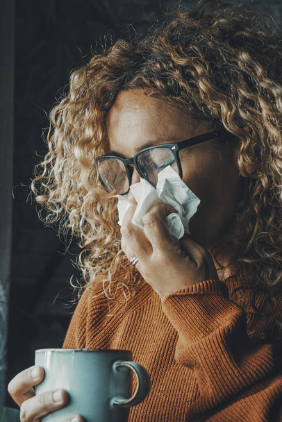 woman sneezing nose with fever and influenza virus health disease. Flu and cold for winter temperature at home. People suffering for unhealthy bad condition indoor. Female with paper towels - Fotografie, Obrázek