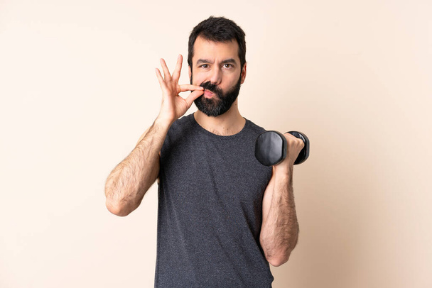 Caucasian sport man with beard making weightlifting over isolated background showing a sign of silence gesture - Photo, Image