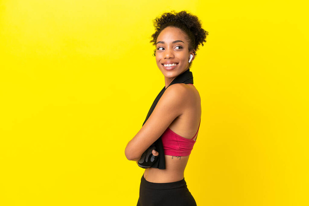アフリカの若いスポーツ女性は,腕が交差して幸せな黄色の背景で孤立しました - 写真・画像