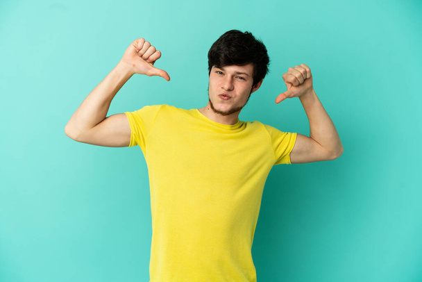Young Russian man isolated on blue background proud and self-satisfied - Photo, Image