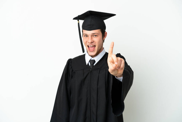 Молодой выпускник российского университета выделяется на белом фоне, показывая и показывая пальцем - Фото, изображение