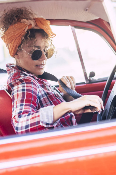 Frau mit Sicherheitsgurt im Auto von außen betrachtet - Versicherungskonzept und Fahrerin - trendige junge Frau genießt Reisen und fährt Fahrzeug für Transportaktivitäten - Foto, Bild