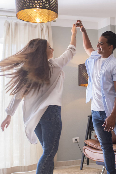 Longitud completa de pareja joven y despreocupada bailando juntos en casa - Foto, Imagen
