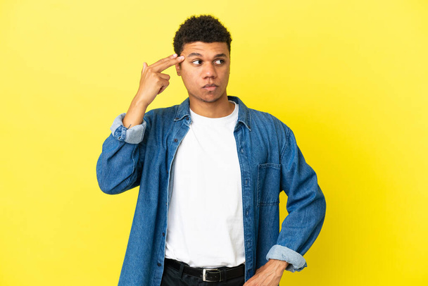 Joven afroamericano aislado sobre fondo amarillo con problemas para hacer gesto suicida
 - Foto, imagen