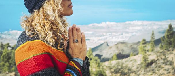 Close-up of calm young Caucasian woman holding hands on heart chest and feeling grateful and grateful. Happy female shows gratitude, love and care, prays or displays. Religion, faith concept. - Photo, Image