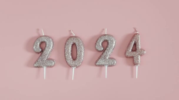 Un conjunto de nuevas velas brillantes de vacaciones número 2024 se encuentran en una fila sobre un fondo rosa, plano de primer plano con zoom. - Metraje, vídeo