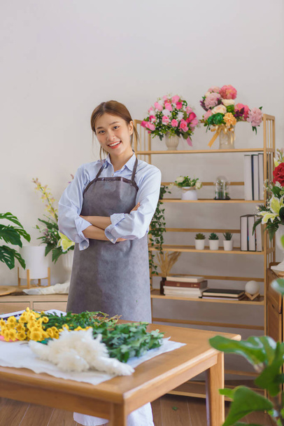 Florist concept, Woman florist wear apron and stand to smiling with arms crossed in flower shop. - Φωτογραφία, εικόνα