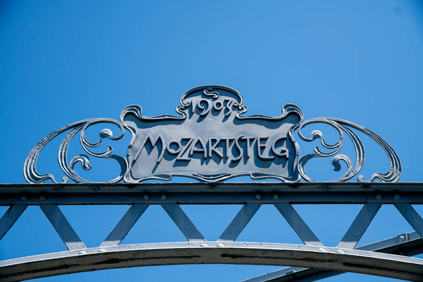 Het Mozartsteg bord met de Duitse letters: Mozartsteg. Gemaakt van metaal, met reliëfletters en het jaar 1903 tegen een blauwe lucht - Foto, afbeelding