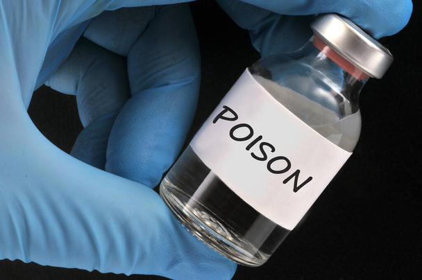 Concept of poison bottle held by gloved hand close-up on black background  - Photo, Image