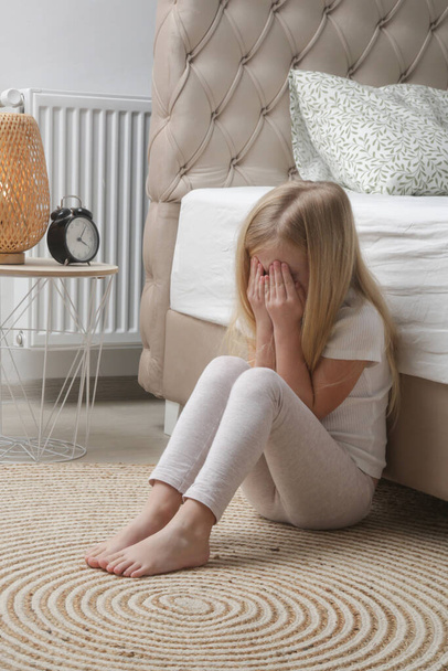 Little girl sitting in the bedroom, crying and covering face with hands - Foto, Bild