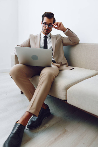 Man looking business sofa smiling modern watching using leisure handsome technology casual working lifestyle attractive adult call home online sitting couch laptop house networking video - Photo, Image