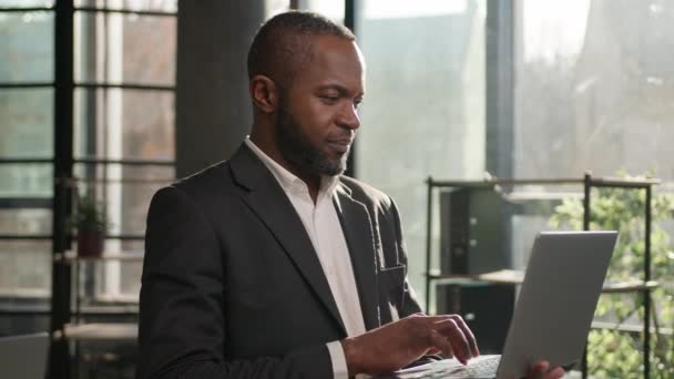 アフリカ系アメリカ人ビジネスマン成人40代中年のビジネスマンは屋内で日当たりの良い日光でラップトップと立っています. 笑顔の男性雇用主CEO コンピュータのオンラインデータ解析プログラミング - 映像、動画