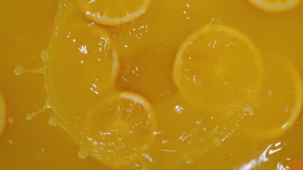 Крупним планом падаючі нарізані лимони, апельсини та лимони у воду на помаранчевому тлі, роблячи коктейль з цитрусових, п'ючи холодний лимонад, стріляючи газованою водою з нарізаними фруктами
. - Кадри, відео