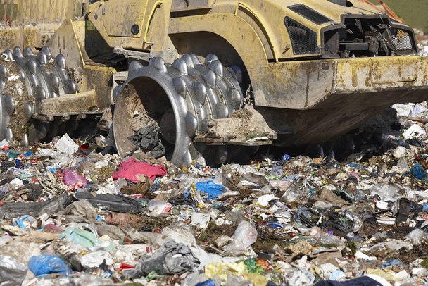Heavy machinery shredding garbage in an open air landfill. Waste - Zdjęcie, obraz