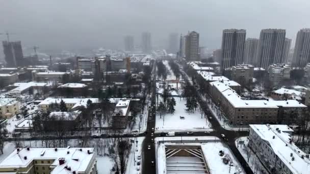 Invierno Dnipro ciudad en Ucrania y la nieve cubierta calle con el tráfico de coches de una vista de pájaro durante las nevadas. Vista aérea de drones de carreteras y rascacielos. Vista aérea de la ciudad cubierta de nieve. - Imágenes, Vídeo