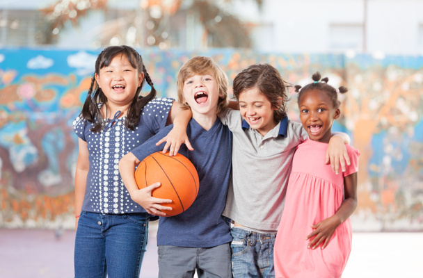 Peruskoulun lapset onnellinen pelaa koripalloa koulussa
 - Valokuva, kuva