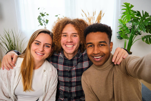 Grupo de três amigos felizes multiétnicos tirando uma selfie em casa. Retrato de pessoas sorridentes. - Foto, Imagem