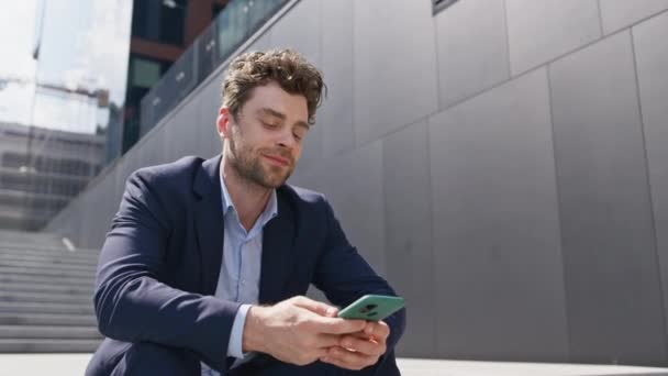 Company worker surfing smartphone internet sitting city stairs sunny day close up. Relaxed handsome man looking cellphone screen relaxing at urban district. Elegant businessman reading message outdoor - Footage, Video